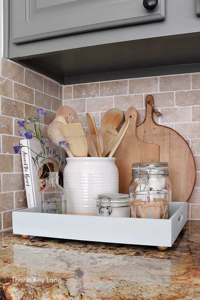 Cutting boards, utensils in a crock and jars on a tray. How To Decorate A Tray With Wallpaper.
