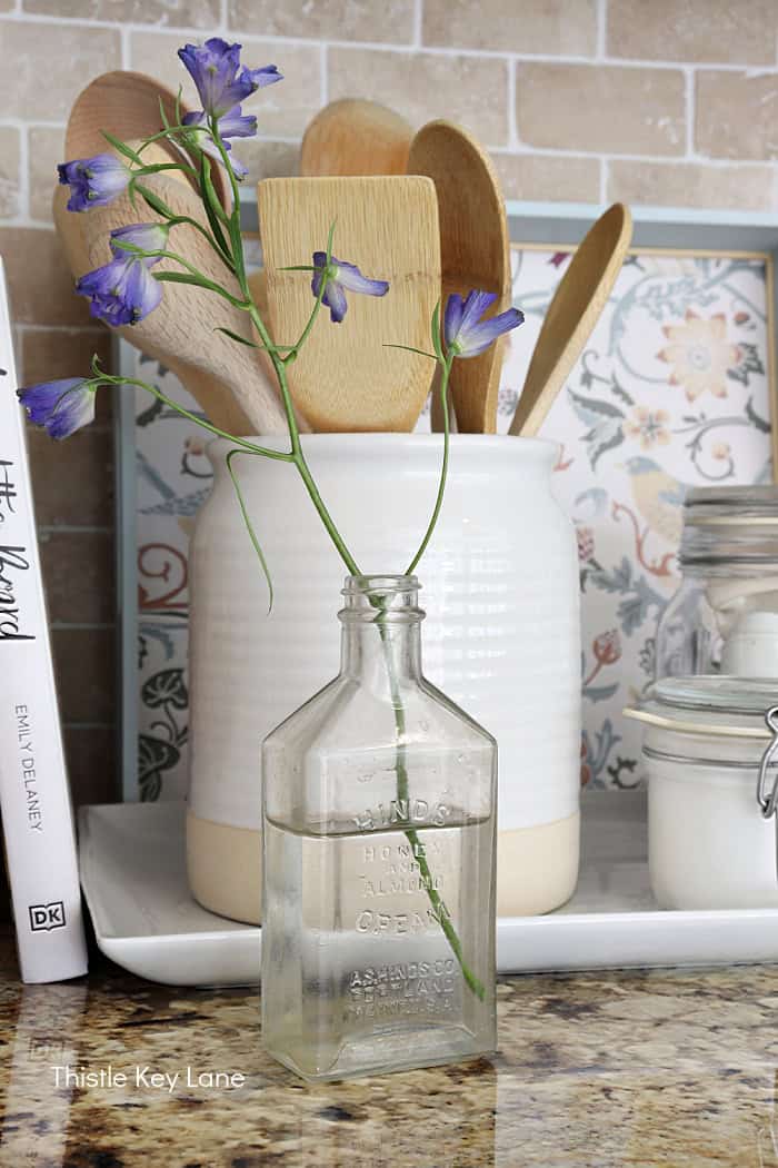 Tray in background behind crock holding utensils and vintage bottle. How To Decorate A Tray With Wallpaper
