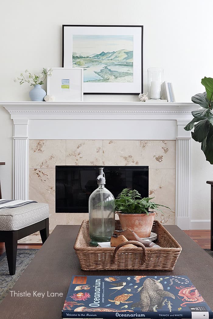 Fireplace with large painting, books, candle holder and vase.