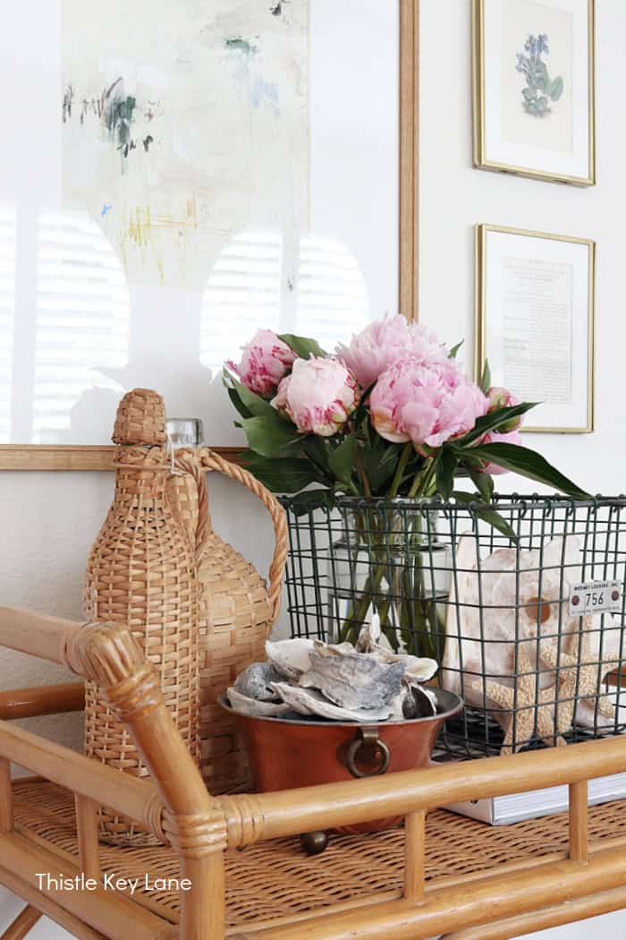 Pink peonies, wire basket and wicker bottles. Coastal Family Room Styling.