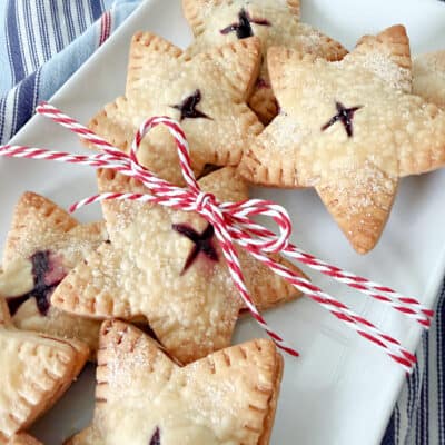 Baked goods on a tray with a red and white string bow. Star Blueberry Hand Pies Recipe.