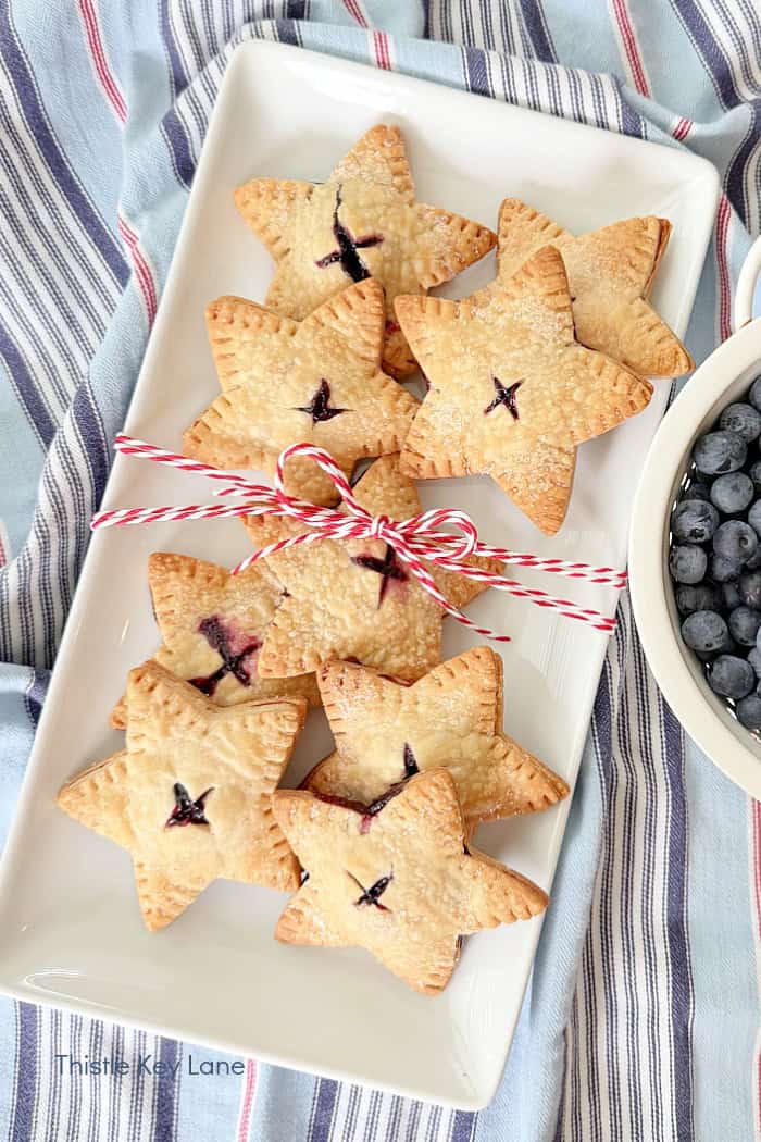 Blueberries in a bowl next to a tray of baked stars. Star Blueberry Hand Pies Recipe.