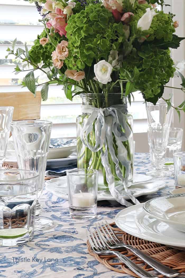 Silk ribbon bow on a vase of flowers. French Country Style Table Setting.