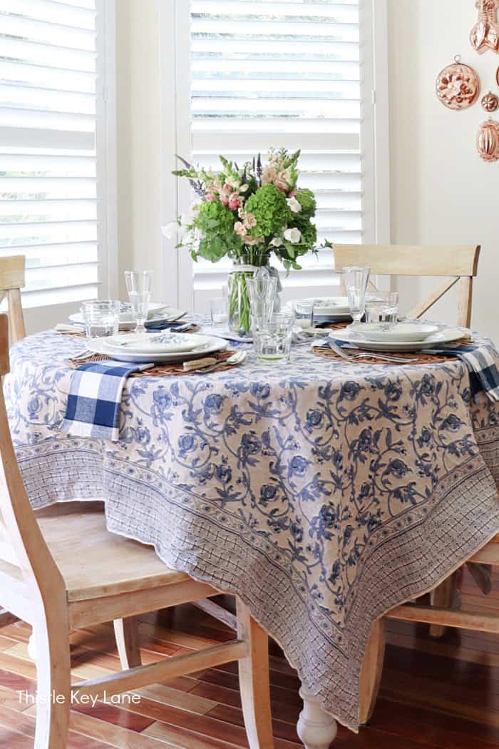 Long tablecloth on a round table with flowers. French Country Style Table Setting.