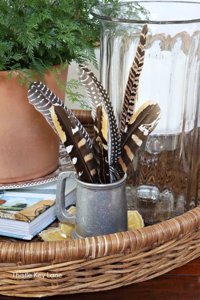 Pewter mug, feathers, book, terra cotta flower pot. Early Fall Entry Table With Greenery.