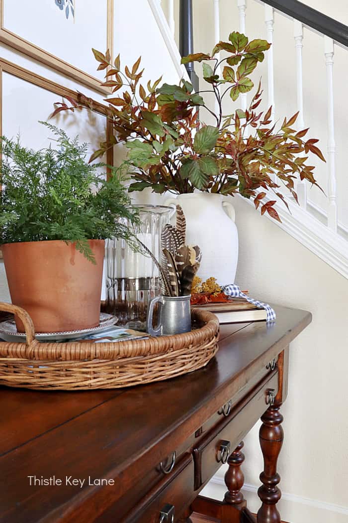 Cream colored urn with fall branches. Early Fall Entry Table With Greenery.