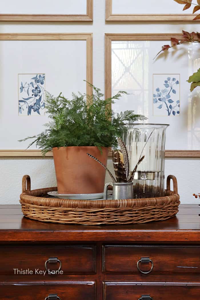 Wicker tray, fresh fern, candle holder. Early Fall Entry Table With Greenery.