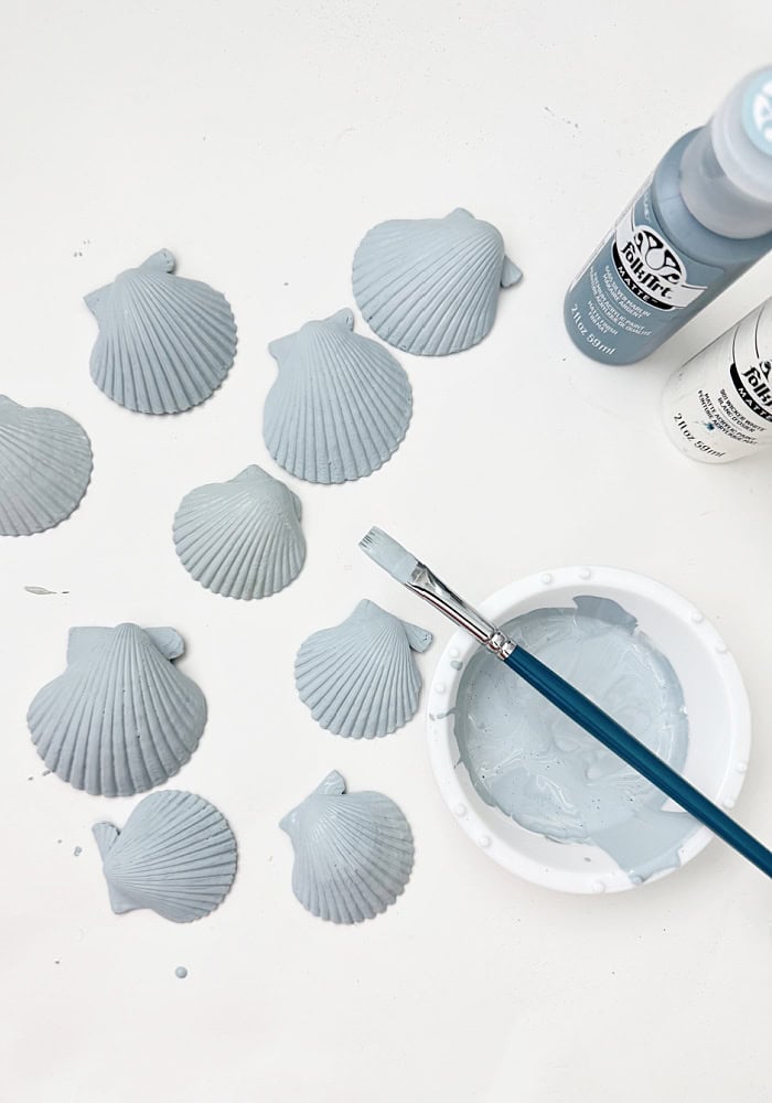 Paint bottles, paint brush and shells.
