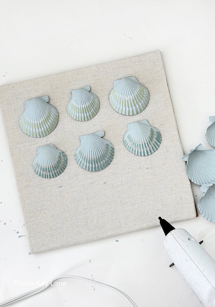 Hot glue gun and shells on a linen board. DIY Painted Shell Artwork.