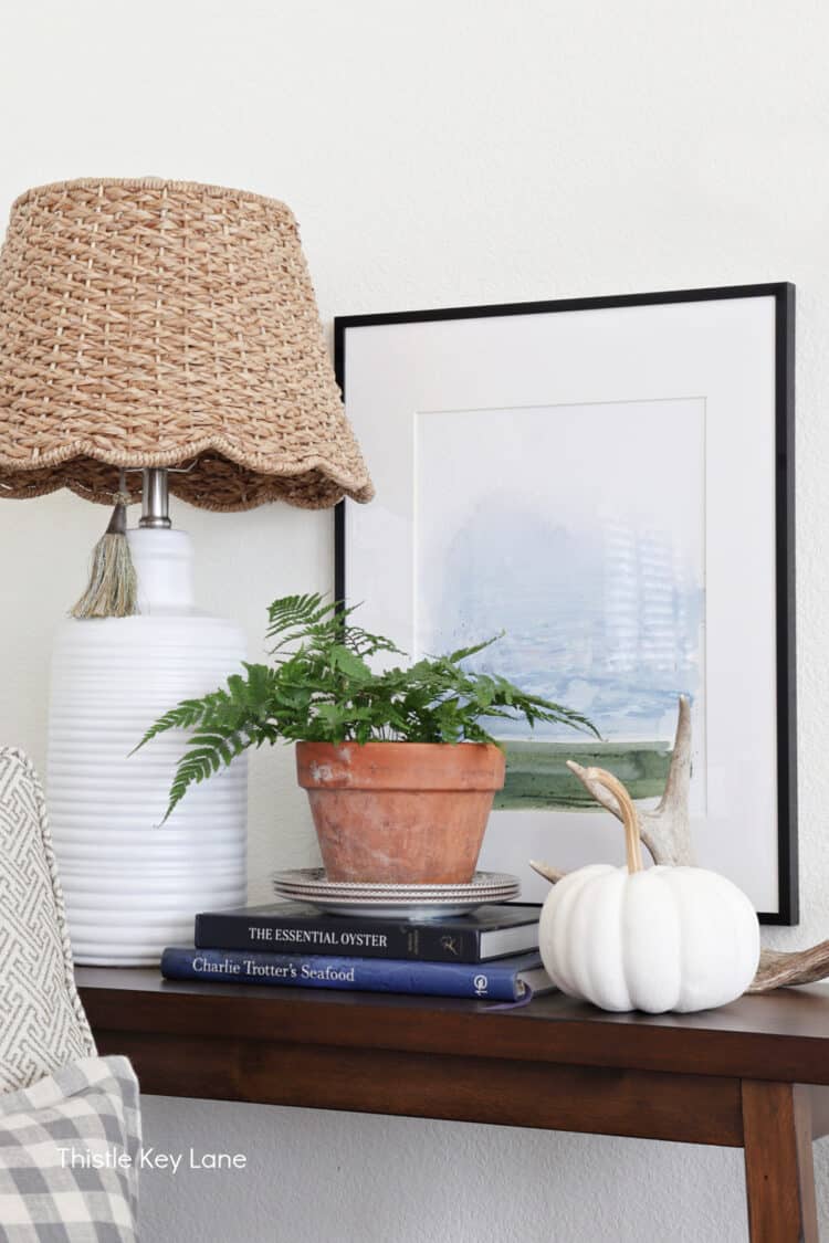 White pumpkin, books, plant and lamp.