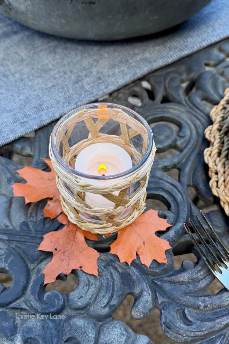 Woven candle holder and fall leaves. Charming Rustic Fall Al Fresco Tablescape Ideas.