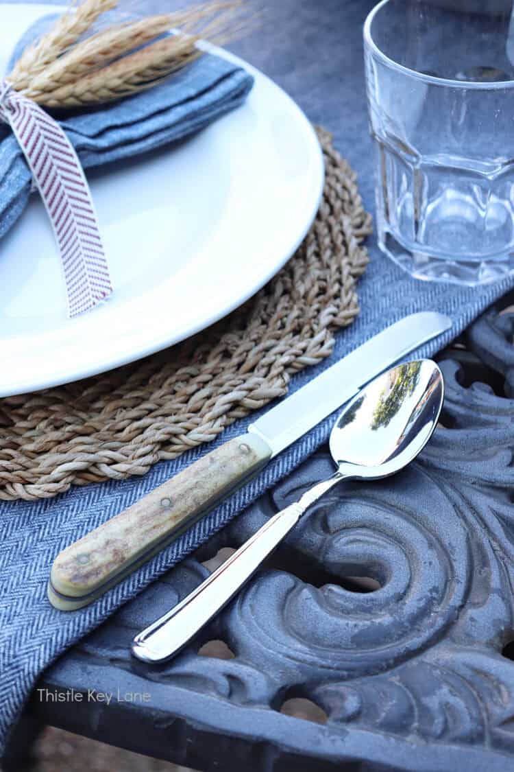Woven charger, white plate and cutlery. Charming Rustic Fall Al Fresco Tablescape Ideas.