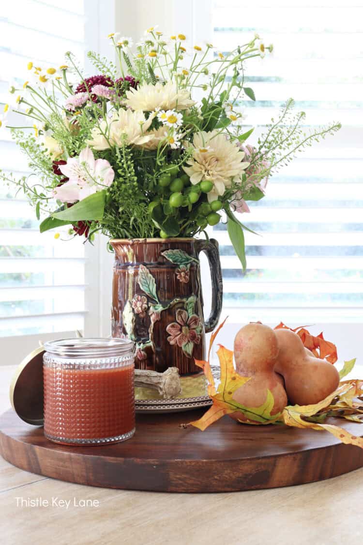 Gourds, flowers, candle. Fall Floral Centerpiece With Vintage Pitcher.