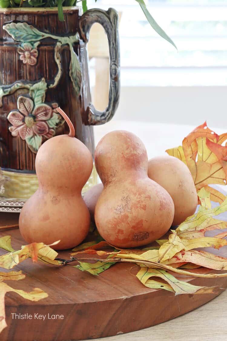 Bottleneck gourds with fall leaves. Fall Floral Centerpiece With Vintage Pitcher.